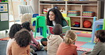 Woman, teacher and storytelling with book in nursery for story time, education or learning. Female person, educator or instructor with elementary children or novel for listening activity in classroom