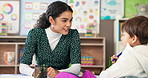 Conversation, education or study with student and teacher in classroom together for development. Learning, lesson or teaching with boy child and woman at desk in school for academic scholarship
