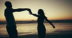 Silhouette, sunset and couple are dancing on beach for love, freedom and travel together for relationship commitment. Trust, care and security of people outdoor, holding hands and moving for romance