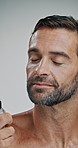 Man, spray and perfume in studio with cosmetics, aftershave and eyes closed for scent by background. Mature person, model and cologne bottle for fragrance, self care or grooming with morning routine