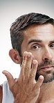 Mature man, skincare and face cream with lotion in studio for facial treatment on a white background. Portrait, male person or model applying cosmetics with creme or moisturizer for skin protection
