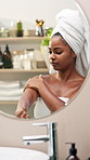 Black woman, lotion and skincare by mirror in bathroom for smooth texture, wellness and moisturizer. Girl, person and self care with cream, cosmetics and routine for beauty with dermatology at house