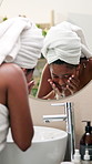 Woman, washing face and mirror in bathroom with water drops, cleaning and skin routine for beauty in morning. African girl, splash and liquid for facial hygiene, process and dermatology at apartment