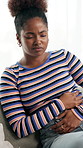 Black woman, stomach ache and pain with nausea for gastrointestinal disease on sofa at home. Sick, female person or tummy cramps with discomfort for diarrhea, menstruation cycle or period at house
