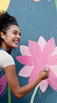 Girl, painting and mural on wall with flowers, smile and art with design for community in urban town. Woman, painter and happy with social responsibility, creative or volunteer for building in Brazil