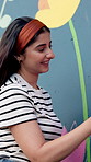 Woman, painting and mural on wall with flowers, smile and art with design for community in urban town. Girl, painter and happy with social responsibility, creative and volunteer for building in Peru