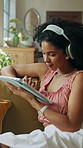 Headphones, tablet and woman relaxing on sofa in home on app for listening to music, podcast or radio. Digital technology, calm and female person streaming album, playlist or song in living room.