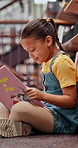 Child, reading and book on floor in library for knowledge, fantasy story and language development. Student, study and creative novel and academic growth, literature and information of education goals