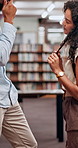 University, couple and conversation at school in library for laugh, college education or knowledge with books. Man, woman and students in campus for flirting, joke and studying for scholarship