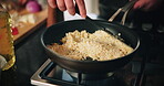 Cooking, hands and rice with person in kitchen of home for preparation of meal or supper. Frying pan, risotto and stove with chef at counter in apartment for diet, health or nutrition closeup