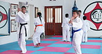 Children, learning karate and training in class with instructor for fight, fitness or self defense. Students, kids and people practice martial arts, kick and exercise for lesson with teacher in dojo