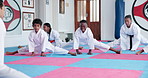 Group, karate and stretching with kids in gym for start of martial arts or self defense class. Exercise, fitness and warm up with happy children in dojo for combat sports, training or workout