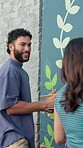 Man, woman and painting by wall for mural with flowers, art and talking for community in urban town. People, painter and smile for social responsibility, creative and volunteer for building in Brazil