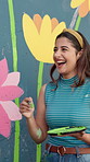 Woman, playful and laugh with mural by with flowers, art or help for community project in town. People, team and funny joke with charity for social responsibility, creative and game with volunteering