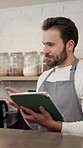 Coffee shop, barista and man with tablet for online sales, order update or check inventory. Digital technology, cafe and waiter on internet for customer reviews, stock or discussion for planning menu