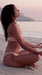 Woman, meditation and lotus at beach, sunset or outdoor for breathing exercise, bikini or zen with mindfulness by sea. Girl, yoga and peace on ground, swimwear and holiday by ocean in Costa Rica