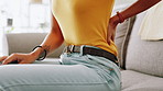 Home, hands and woman on sofa, back pain and inflammation with discomfort. Closeup, apartment and person on couch, bruise and ache with muscle tension, burnout and bad posture in living room