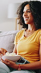 Home, remote control and woman on sofa, popcorn and relax with weekend break in lounge. Apartment, watching tv and happy person on couch, snack and streaming for funny movie, series and entertainment