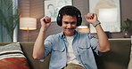 Headphones, dancing and man on sofa in home for chilling, relaxing and listening to music. Audio tech, happy and male person with streaming playlist, song or album on mobile app in living room.