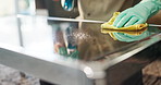 Person, hands and cleaning table with spray for housekeeping, chores or disinfection at home. Closeup, cleaner or maid with detergent, gloves or cloth for bacteria or germ removal on glass surface