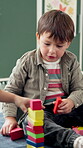 School, child and boy with blocks for education, creative and cognitive development in classroom. Kindergarten, student and kid with building toys for learning, motor growth and problem solving skill
