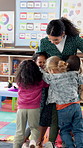 Teacher, hug and woman in classroom, students and smile with education, bonding together and love. Educator, child development and kids in school, kindergarten and learning with support and embrace