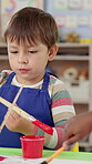 Paintbrush, child student and painting for art at school for learning, creativity and color picture. Education, boy or kids with activity for development with paint and paper for daycare artwork