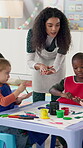 Teacher, painting and kids in classroom for art lesson, explain or show with color, craft and creativity. Drawing, watercolor and woman with students for artwork, paintbrush and preschool activity