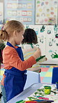 Student, kid and painting on hand in classroom for handprint activity, art project or motor skills development. Kindergarten, girl child and paintbrush for messy artwork, creative lesson or education