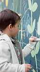 Chalk, drawing and child at preschool for creativity, growth or skill development at mural wall. Education, student and boy kid outdoor with art for activity, hobby or lesson at kindergarten.