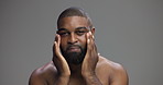 Face, skincare and man with cream in studio for collagen treatment, self care or dermatology. Portrait, moisturizer and African person apply cosmetics for hydration, glow or beauty on gray background