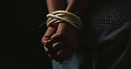 Hands, rope and prisoner or hostage bound and tied up isolated on black background. Capture, fear and danger of person with censorship, bondage and domestic violence with anxiety, depression or crime