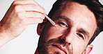 Man, face and oil with serum dropper for vitamin c, collagen or dermatology on a white studio background. Portrait, male person or model applying hyaluronic acid with pipette for facial treatment