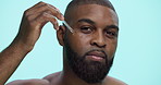 Serum, beauty and face with black man in studio for skincare cosmetics, dermatology and self care. Clean, glow and oil with person and dropper on blue background for hydration, vitamin c and shine