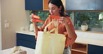 Grocery bags, unpacking vegetables and woman in kitchen for cooking dinner with organic cucumber. Groceries, shopper and unloading food in home, natural ingredients and fresh carrots for healthy diet
