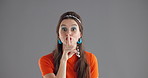 Woman, finger and hush in studio with face, secret and space with smile, flirt or info by background. Girl, happy and model with sign, emoji and icon by lips for silence, privacy and gossip in Greece