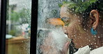 Woman, window and drinking coffee with rain drops for winter season, cold weather or warmth at home. Female person, relax and wonder with cup or mug for caffeine, beverage or indoor comfort at house
