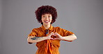 Happy woman, face and studio with heart hands for love, fashion or style on a gray background. Portrait, female person or model with smile, emoji or romantic gesture for shape or icon on mockup space