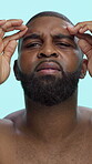 Black man, face and check skin with wrinkles, dermatology and worry for acne on blue background. Cosmetics, serious and antiaging for skincare inspection, forehead and pores for routine in studio