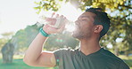 Drinking water, fitness and man in park for training, exercise or workout for health or wellness outdoors. Tired runner, athlete or person with liquid bottle for cardio, hydration or marathon break