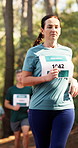 Marathon, woman and running competition in forest for fitness challenge, sports event and stamina. Runner, mature person and group with cardio performance, race endurance and pace training in nature