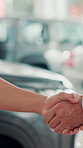 Deal, car and keys with handshake of people at dealership for test drive, auto showroom and vehicle decision. Salesman, purchase and shaking hands with closeup of customer for rental agreement