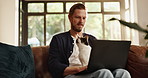 Remote work from home, thinking and man with cat, laptop and problem solving with online editing. Person, freelancer and writer on couch, pc and research for article, creativity and pet owner