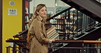 Happy woman, student and walking in library with books for learning, education or study material. Female person, academic scholar or learner with textbook or novel pile for knowledge at university
