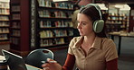 Laptop, woman and student with headphones in university studying for exam with textbooks in library. Education, computer and person writing with learning for college test or assignment on campus.