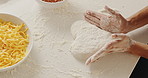 Dough, hands and chef in kitchen for cooking with heart shape for pizza with ingredients for dinner. Top view, cheese and person with culinary skills for preparing food with pastry on table in home.