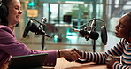 Podcast, interview and women with mic, handshake or live stream of audio conversation or broadcast. Radio, journalist and people with headphones for sound, production and shaking hands for talk show