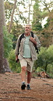 Walking, hiker and man with backpack in nature, journey or holiday for adventure in woods or active. Outdoor, trekking and senior person in forest for vacation, hiking or exploration for fitness