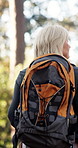 Hiking, backpack and woman walk in woods for travel, sightseeing or thinking in retirement. Trekking, back and senior person in forest for vacation, holiday or explore with reflection for adventure