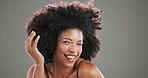 Afro, wind and beauty with black woman in studio for curly hair care, texture and cosmetics. Volume, keratin and shine with person on gray background for growth, smile and natural transformation